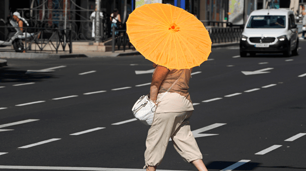 A woman crosses the street with a sun umbrella